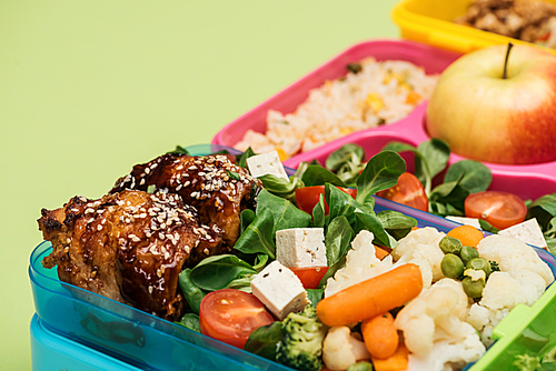 close up view of meal in lunch boxes isolated on green