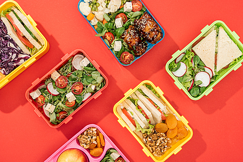 top view of lunch boxes with food on bright red background