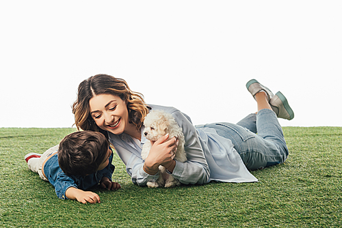 smiling mother holding Havanese puppy and son looking at it isolated on white