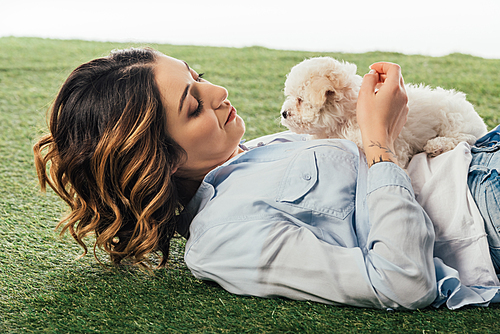 woman lying on grass and looking at Havanese puppy isolated on white