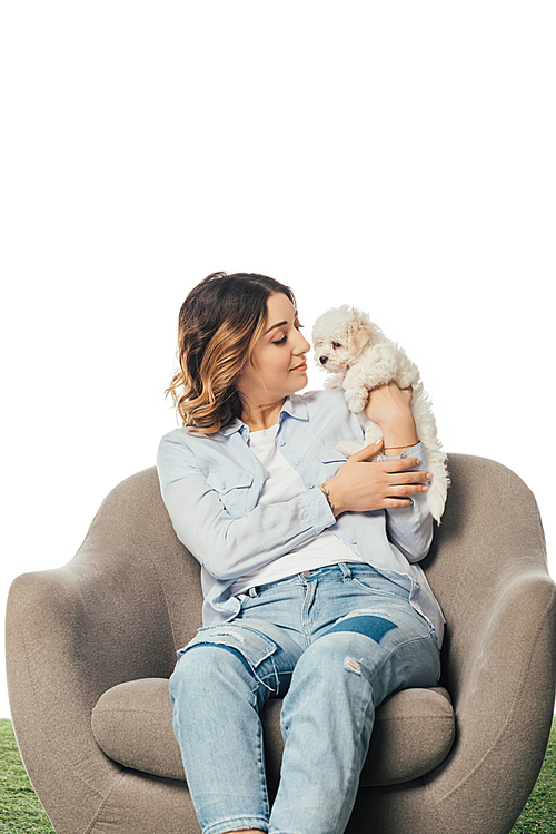 smiling woman holding Havanese puppy and sitting on armchair isolated on white