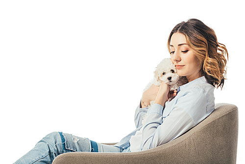 woman holding Havanese puppy and sitting on armchair isolated on white