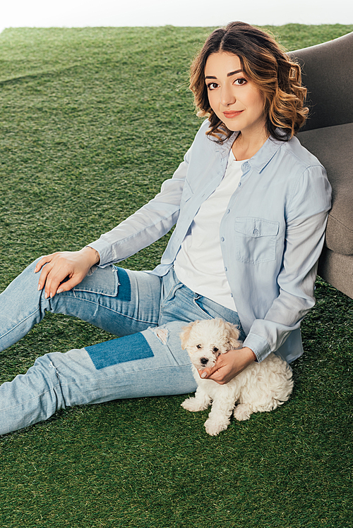 smiling woman with cute Havanese puppy sitting on grass