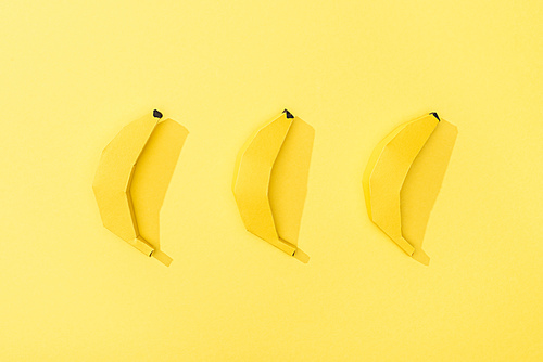 top view of handmade paper bananas arranged in row on yellow
