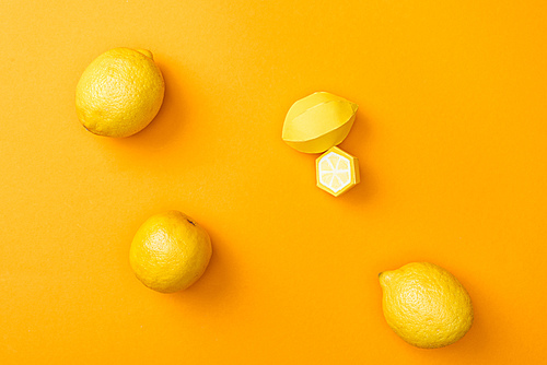 top view of handmade paper lemons and whole ripe lemons isolated on orange
