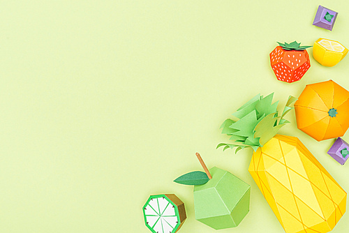 top view of handmade colorful origami fruits isolated on green with copy space