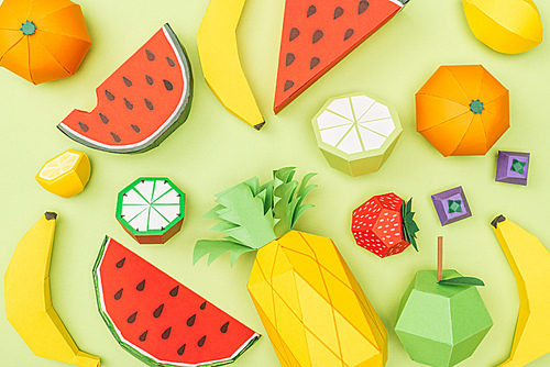 top view of various handmade colorful origami fruits isolated on green