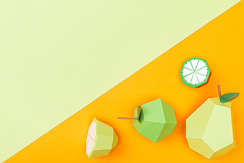 top view of handmade colorful origami fruits on orange and green with copy space