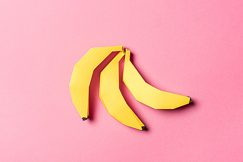 top view of yellow paper bananas on pink