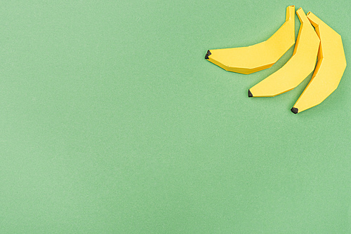 top view of yellow paper bananas isolated on green with copy space