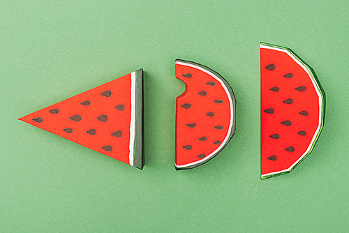 top view of handmade paper watermelon slices isolated on green