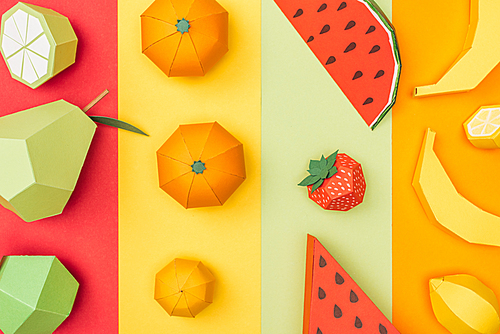 top view of various origami fruits on colorful paper stripes