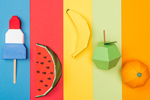 top view of various origami fruits and ice cream on colorful paper stripes