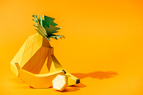 handmade paper pineapple, bananas and lemon on orange with copy space