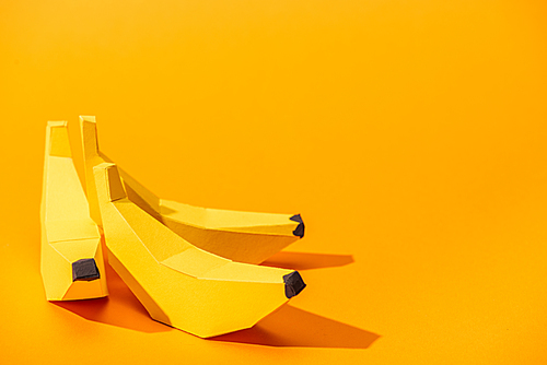 yellow paper bananas on orange with copy space
