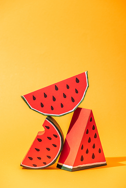 red paper watermelon slices on orange with copy space