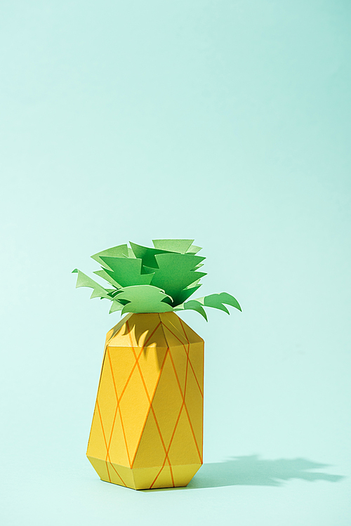 handmade yellow paper pineapple on turquoise with copy space