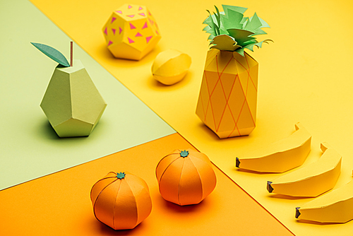 various handmade colorful origami fruits on green, yellow and orange paper