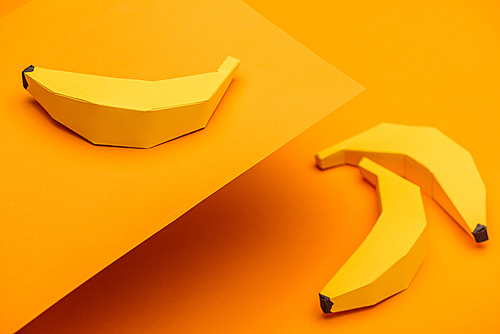background with handmade origami bananas on orange paper