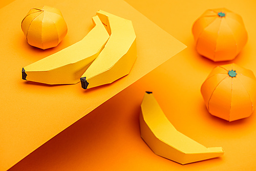 Selective Focus of origami bananas and tangerines on orange