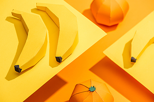 Selective Focus of origami bananas on yellow paper with tangerines on orange