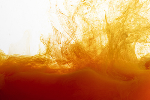 Close up view of orange paint swirls in water
