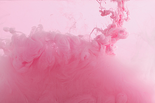 Close up view of pink paint swirls mixing in water