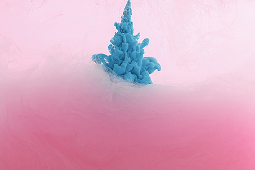 Close up view of blue paint splash in water isolated on pink