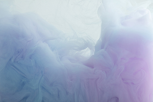 Close up view of light blue and purple paint swirls in water