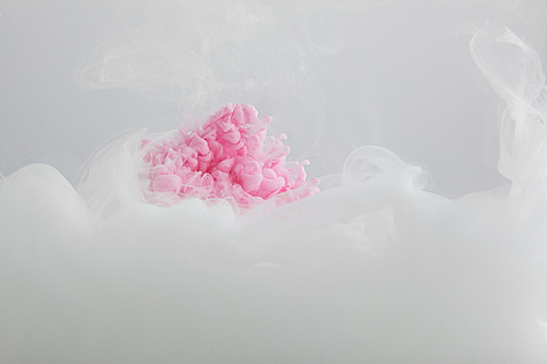 Close up view of pink and white paint mixing isolated on grey