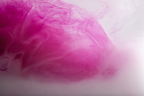 Close up view of bright pink and white paint swirls in water