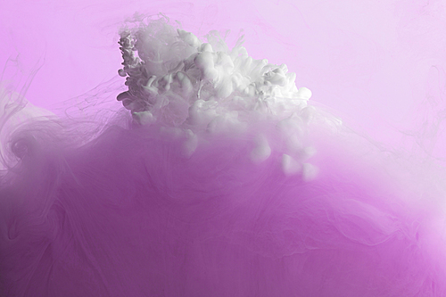 Close up view of pink and white paint mixing in water isolated on pink
