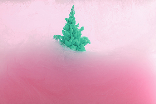 Close up view of green paint splash mixing in pink water