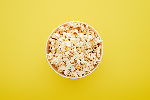 top view of delicious fresh popcorn in bucket on yellow background