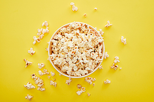 top view of fresh popcorn in bucket on yellow background