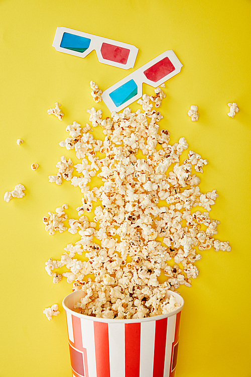 top view of delicious popcorn scattered near 3d glasses on yellow background