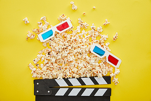 top view of delicious popcorn, 3d glasses and clapper board on yellow background