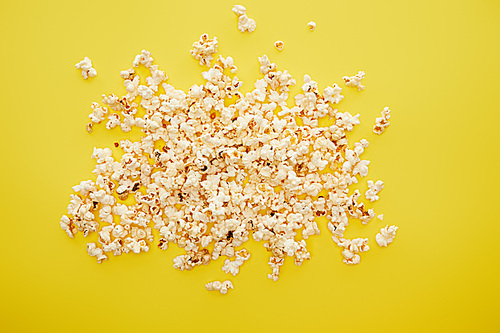 top view of tasty popcorn scattered on yellow background