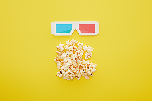 top view of delicious popcorn and 3d glasses on yellow background