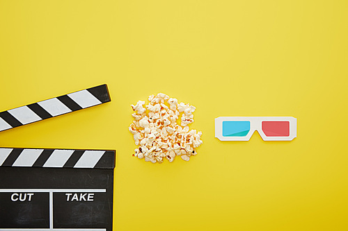 top view of delicious popcorn near 3d glasses and clapper board on yellow background