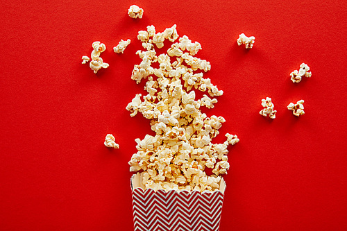 top view of delicious popcorn scattered on red background