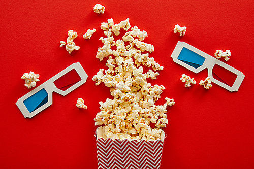 top view of delicious popcorn scattered on red background with 3d glasses