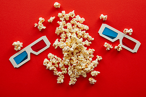 top view of delicious popcorn near 3d glasses on red background