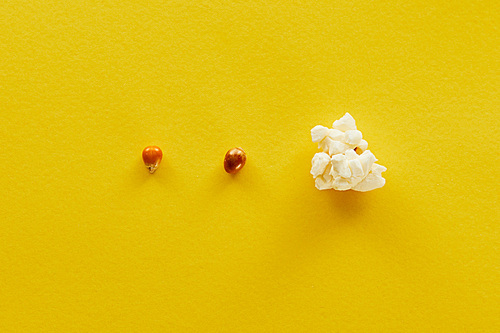 top view of delicious popcorn and corn on yellow background