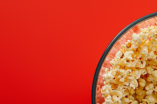 top view of delicious popcorn in glass bowl isolated on red