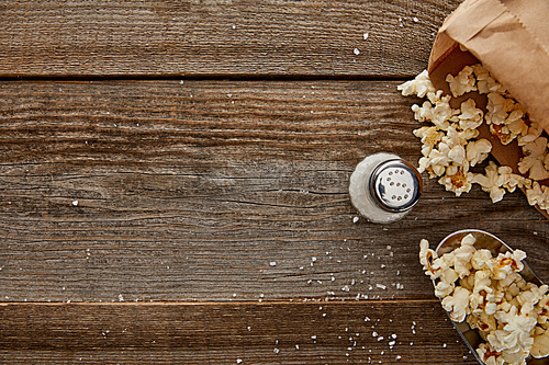 top view of delicious popcorn with salt on wooden background