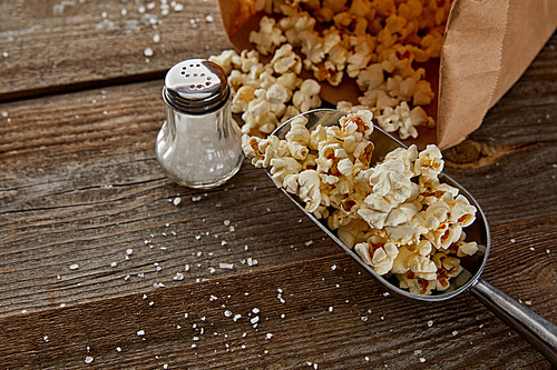 top view of delicious popcorn with salt scattered on wooden background