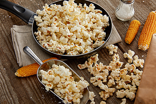 delicious popcorn in frying pan and on wooden table