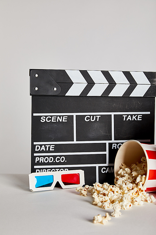 delicious popcorn with clapper board and 3d glasses isolated on grey