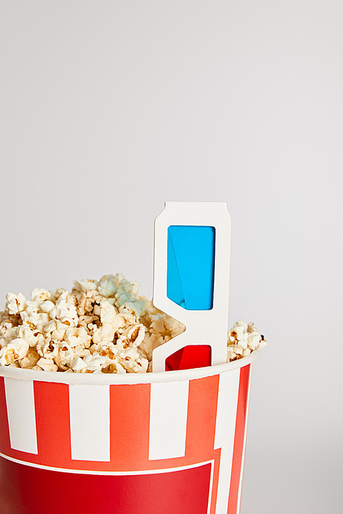 tasty fresh popcorn in bucket with 3d glasses isolated on grey